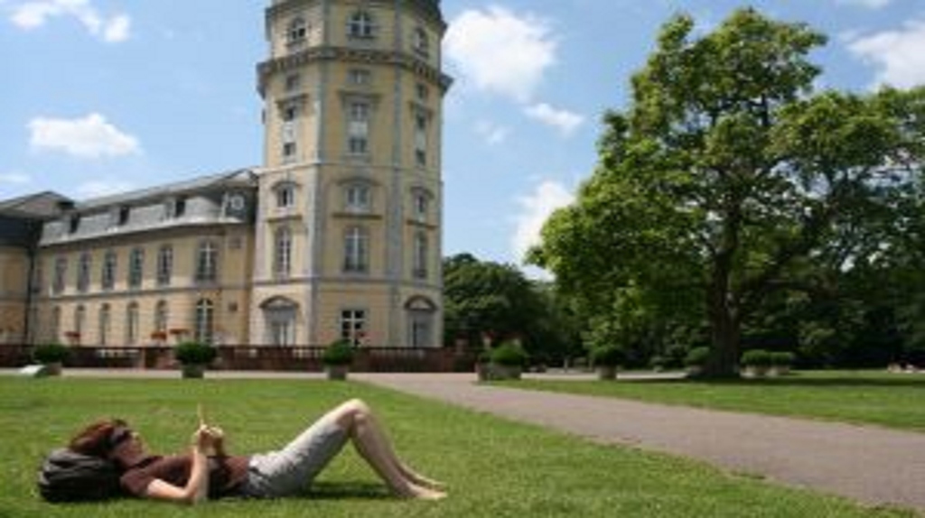 Mensch liegt in Schlosspark vor Schloss Karlsruhe
